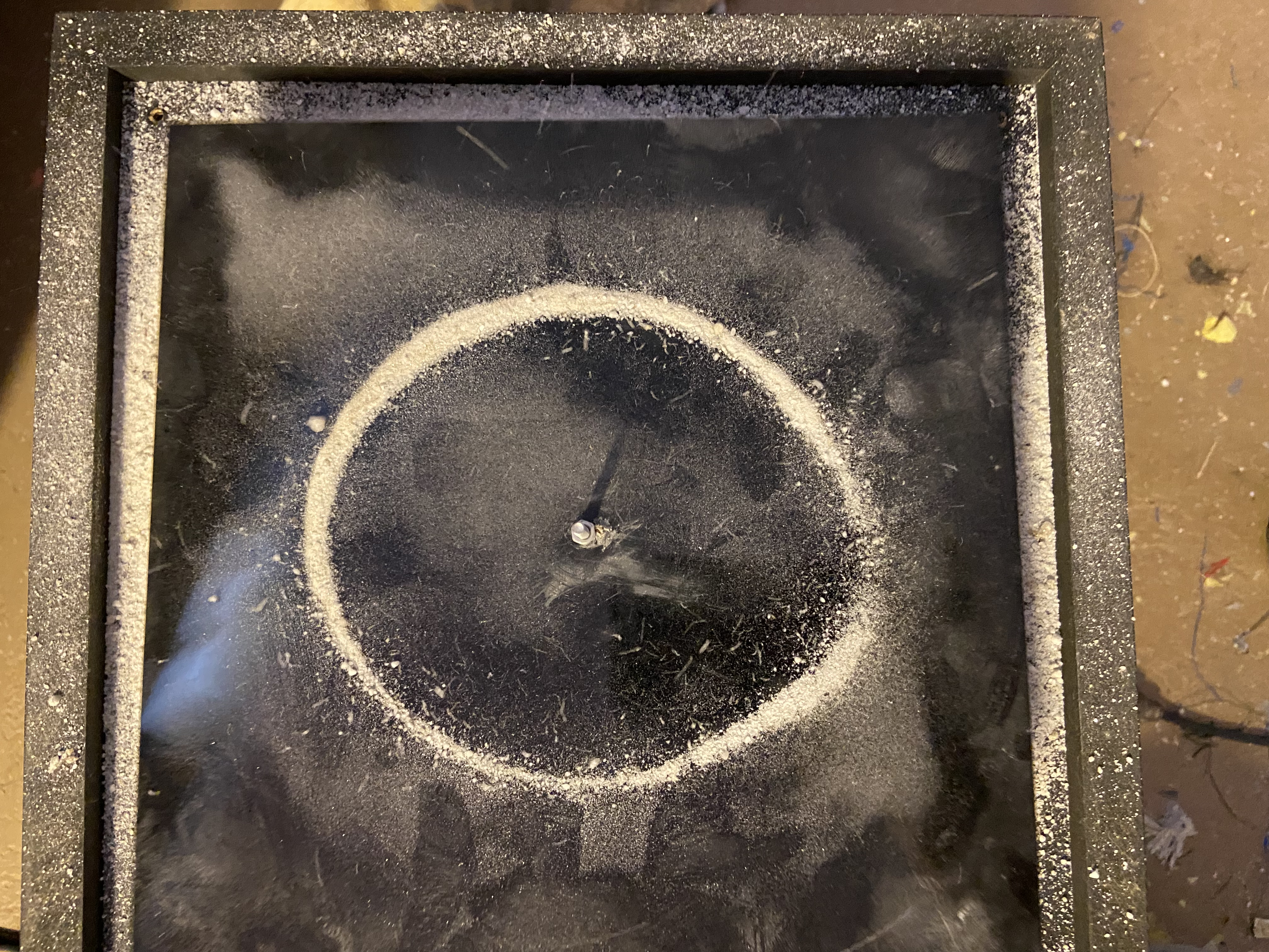 Perfect circle Chladni figure in white sand — single nodal ring on black plate