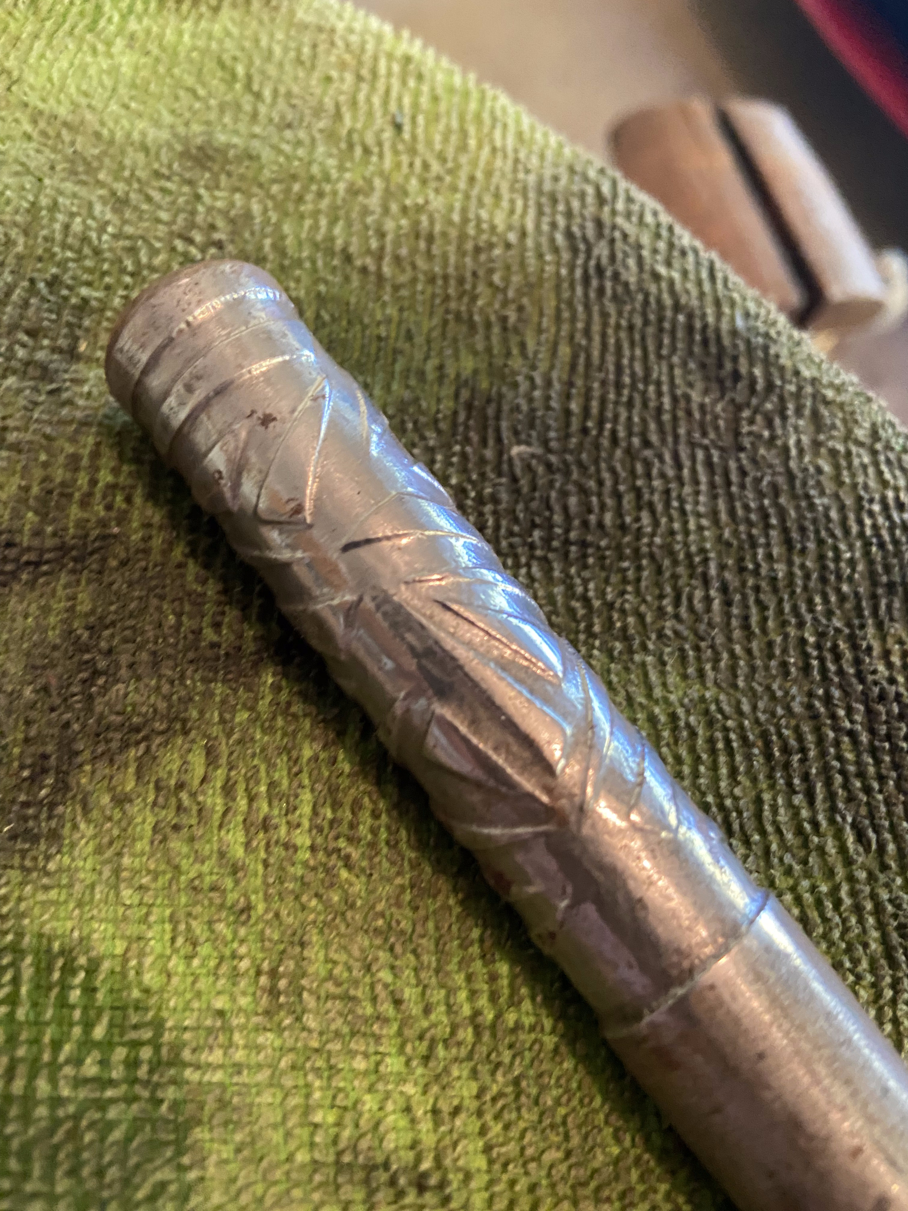Close-up of forged fireplace poker handle showing etched texture on green cloth