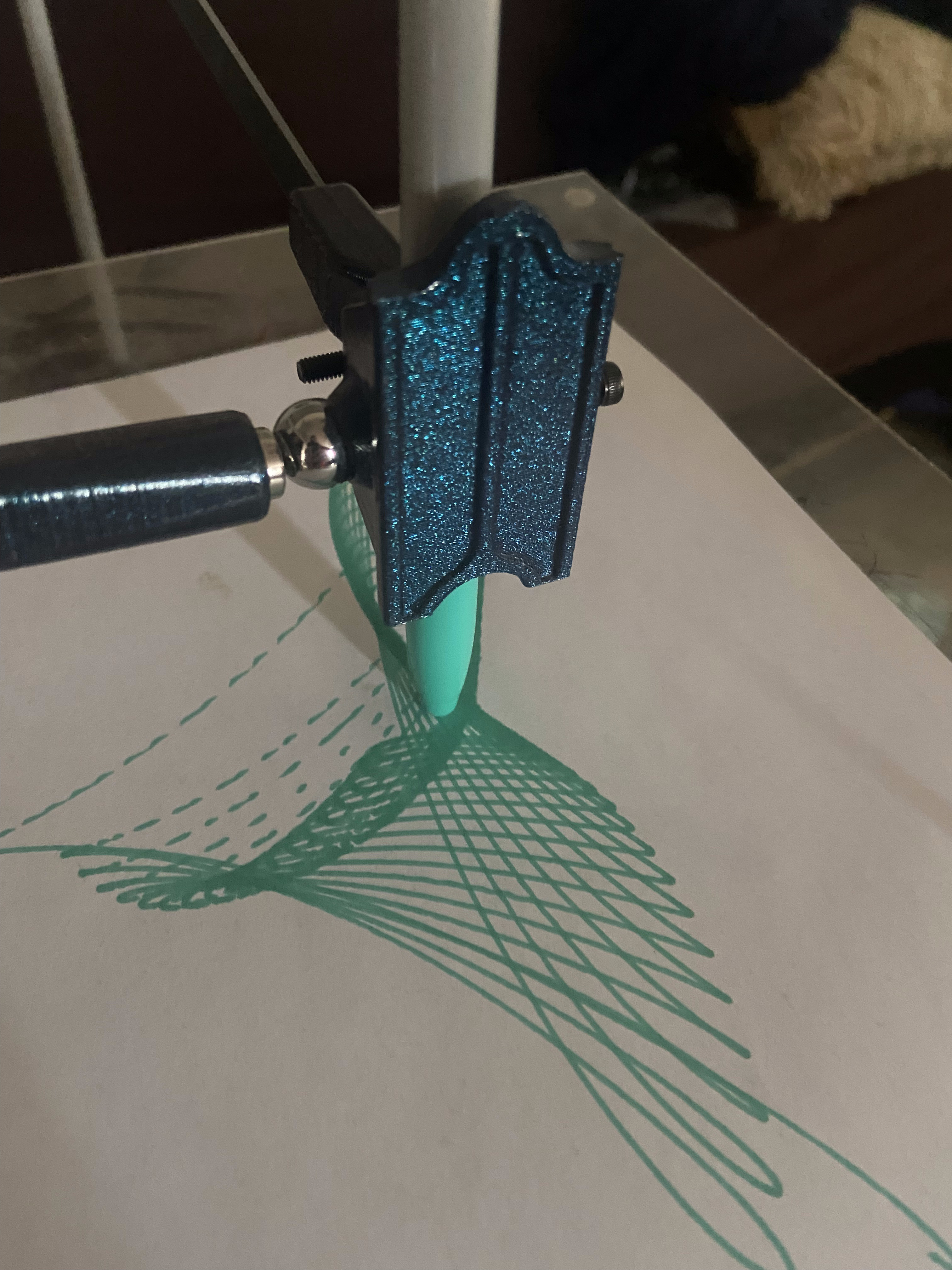 Harmonograph drawing arm actively tracing a Lissajous curve in teal ink