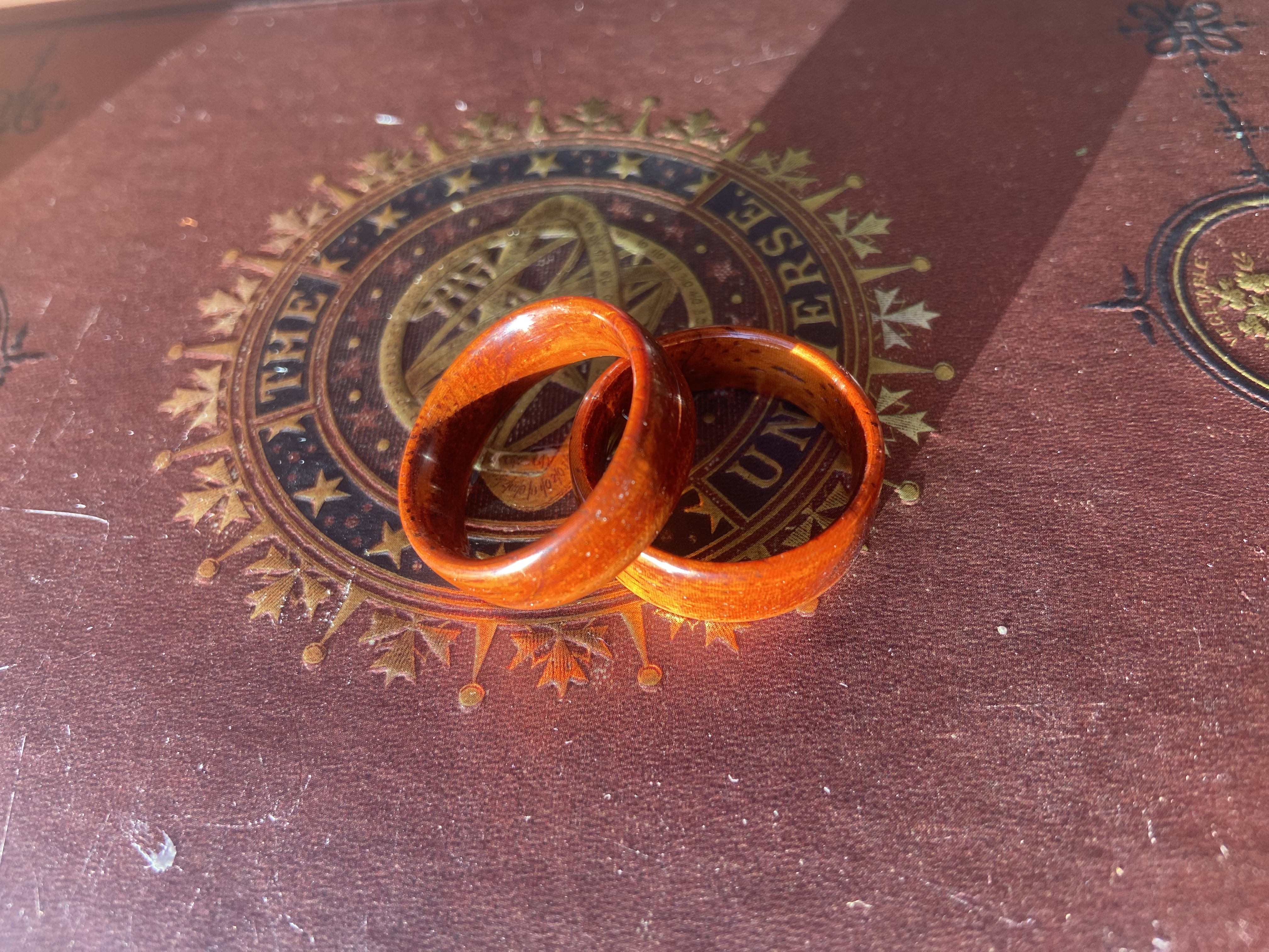 Two amber rings resting on a vintage book cover with gilt lettering