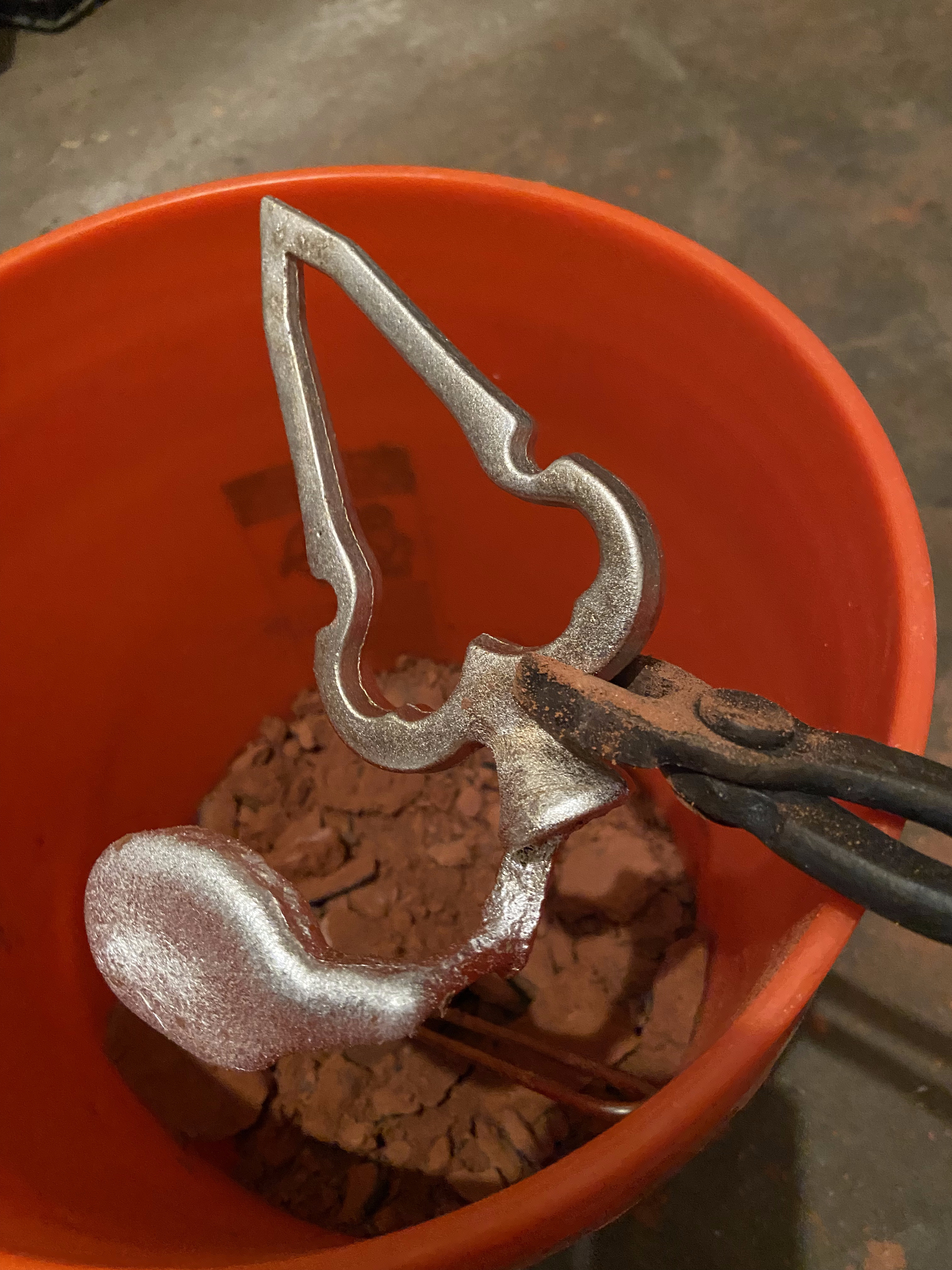 Freshly cast aluminum arrowhead and halberd shapes pulled from petrobond sand
