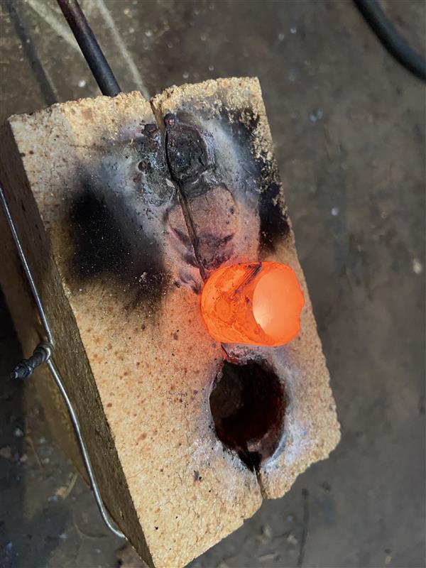 Crucible glowing orange in refractory brick cradle during ruby synthesis firing