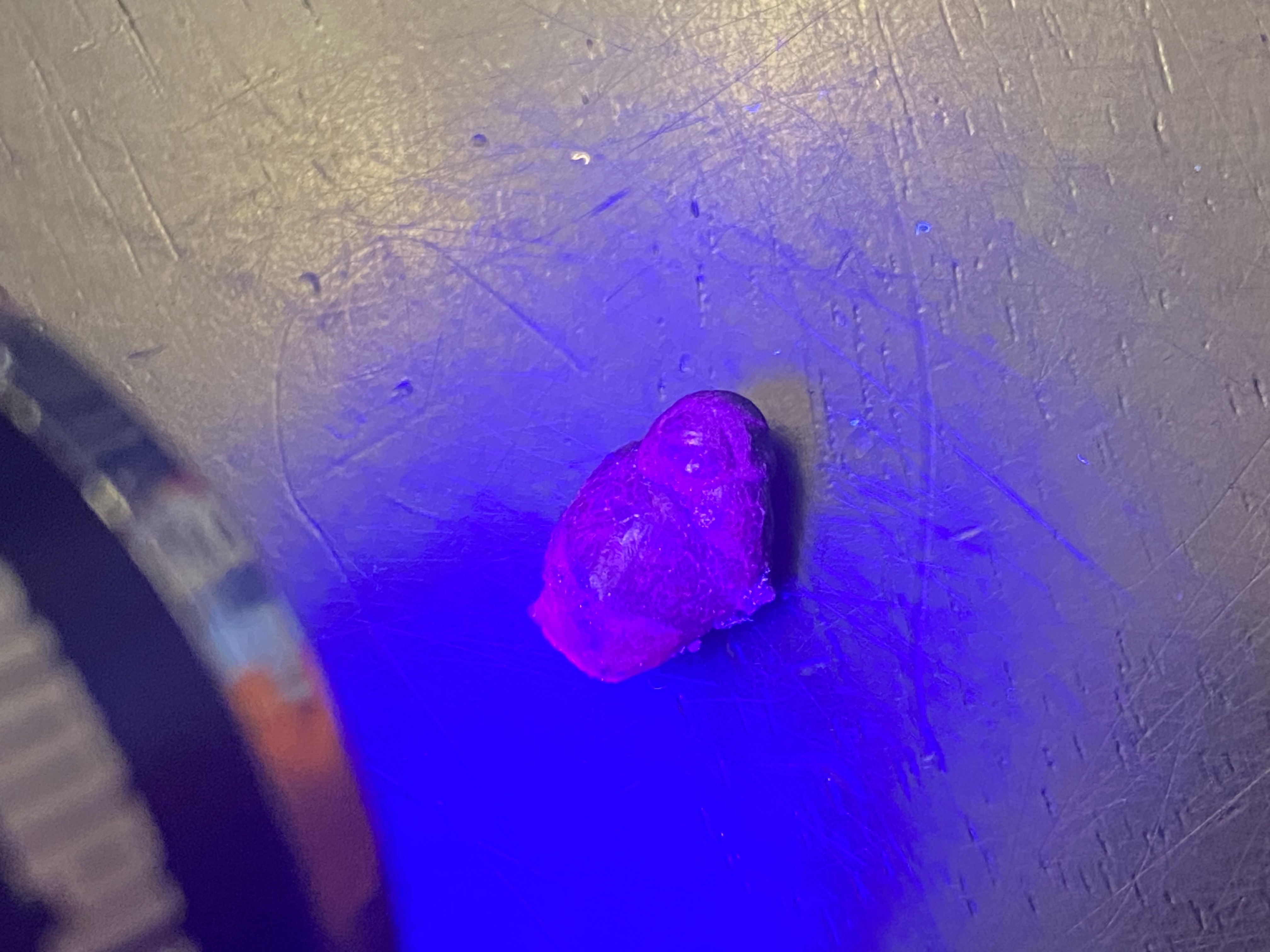Single synthetic ruby crystal blazing bright pink-purple under UV