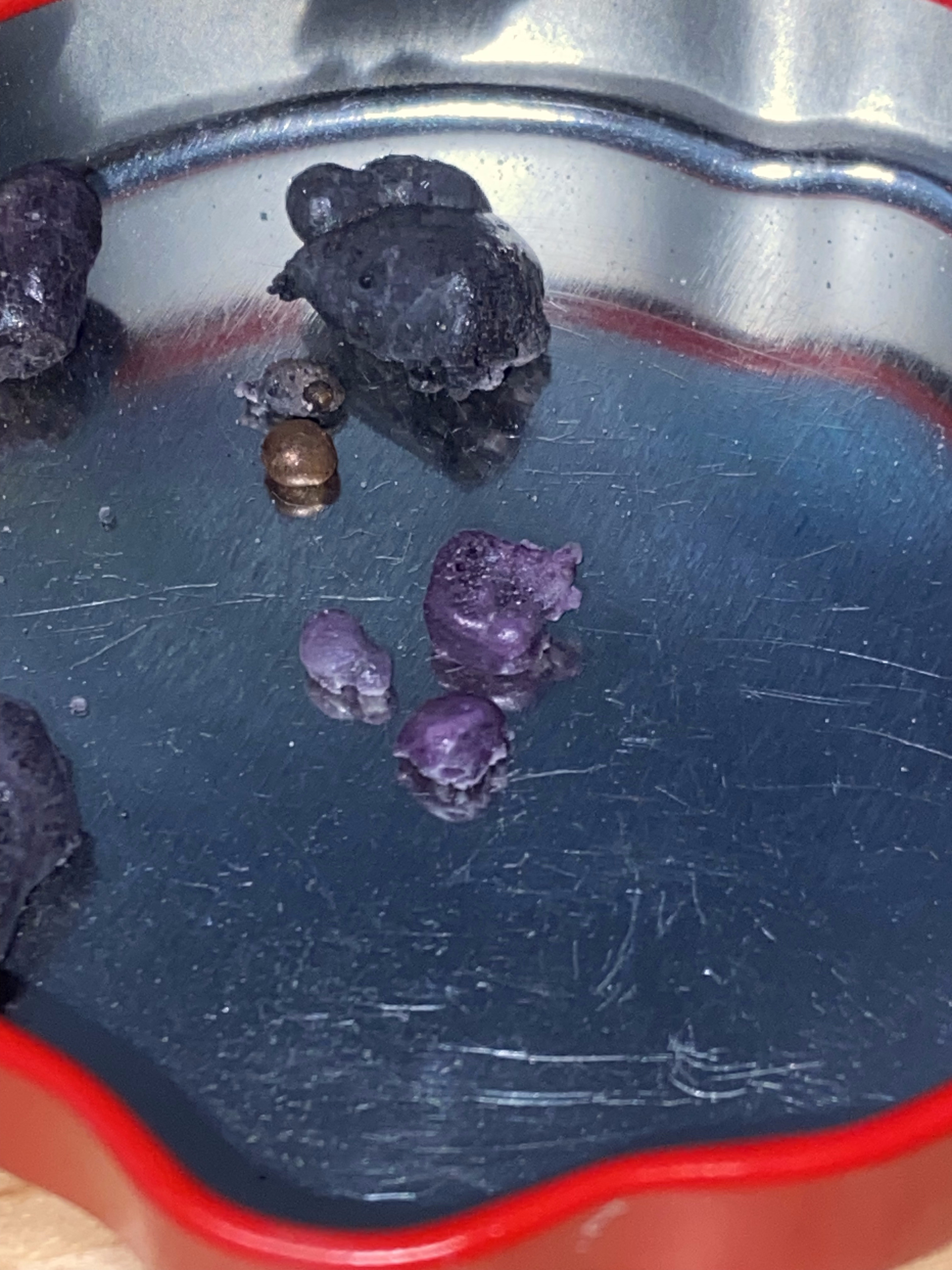 Synthetic ruby specimens in normal light — raw grey-purple corundum before UV illumination